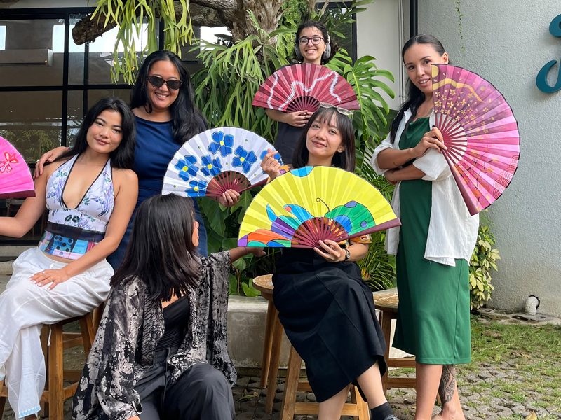 Group photo of guests holding their painted fans in the garden